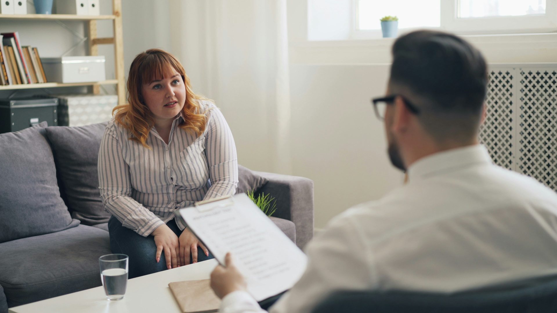a woman sitting on a couch talking to a man